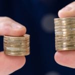 Someone holding two stacks of coins - one bigger than the other