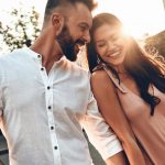 Couple leaning on each other, laughing & holding hands