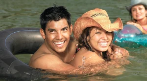 A couple swimming together in the water, smiling and having fun.  (Generated with AI)