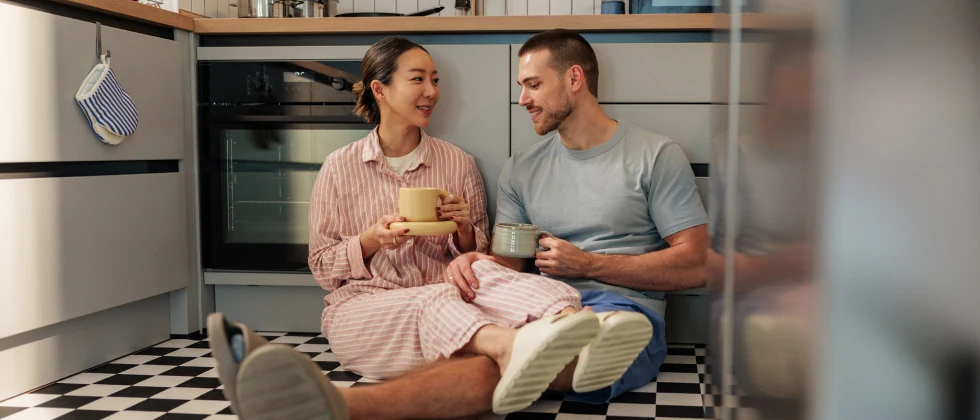 Couple sitting on the kitchenfloor drinking coffee and talking