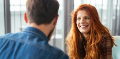 A women smiling and talking to a guy, showing how to ask a coworker out.