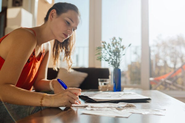 A woman is sitting at a table writing things down