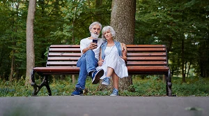 A couple sitting on a bench in a park, chatting. (Generated with AI)
