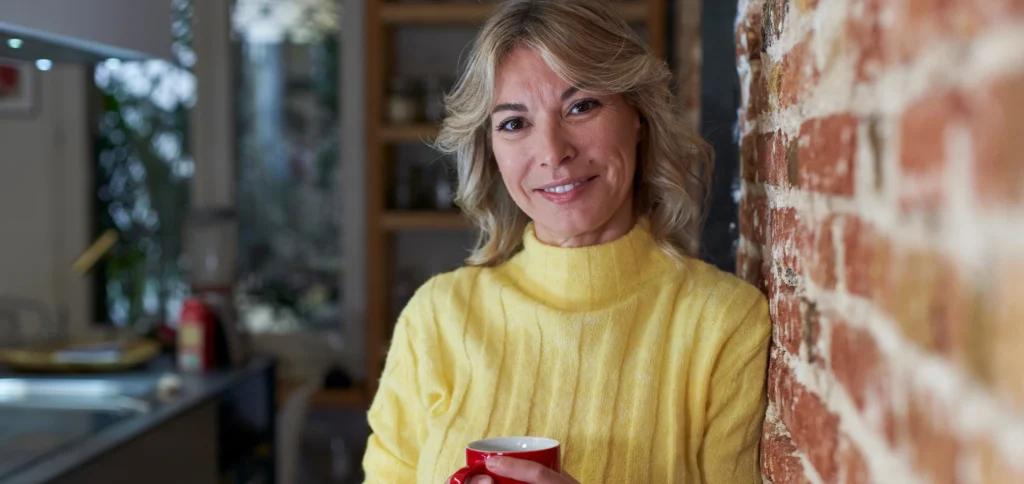 Smiling mature woman holding a coffee cup indoors.