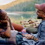 A couple in a tent in nature, talking and eating.