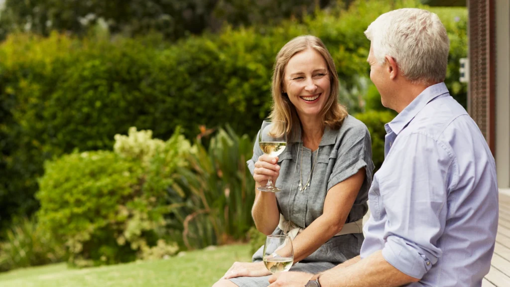 A couple are enjoying a conversation over wine in the garden.
