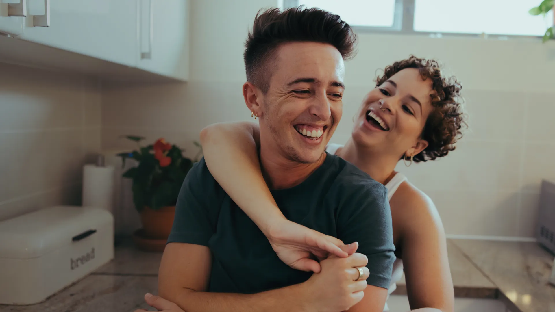 A transgender couple are hugging each other in the kitchen. (Generated with AI)